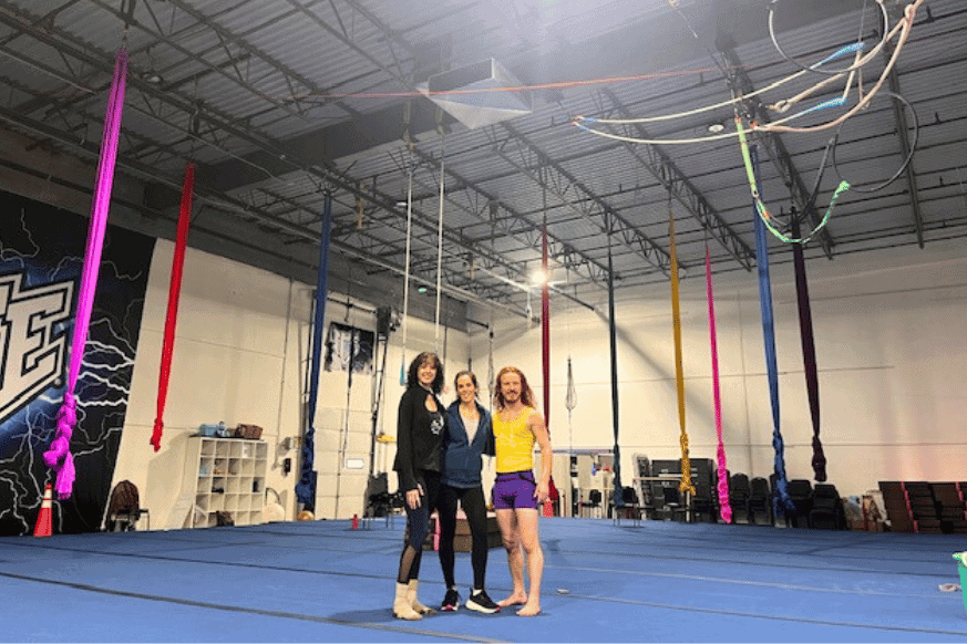 Interior of On The Fly fitness studio with colorful hanging aerial silks. 2 fitness coaches with fitnessfoodiestl 