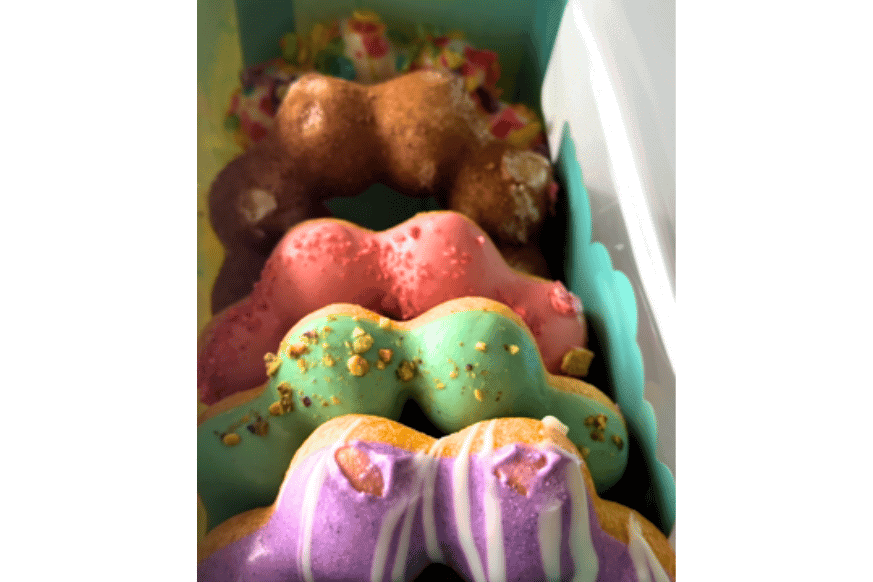 multi flavor box of donuts from mochi donut. that sit up rather than flat. flavors include taro, pistachio, strawberry, churro and milk with pebbles