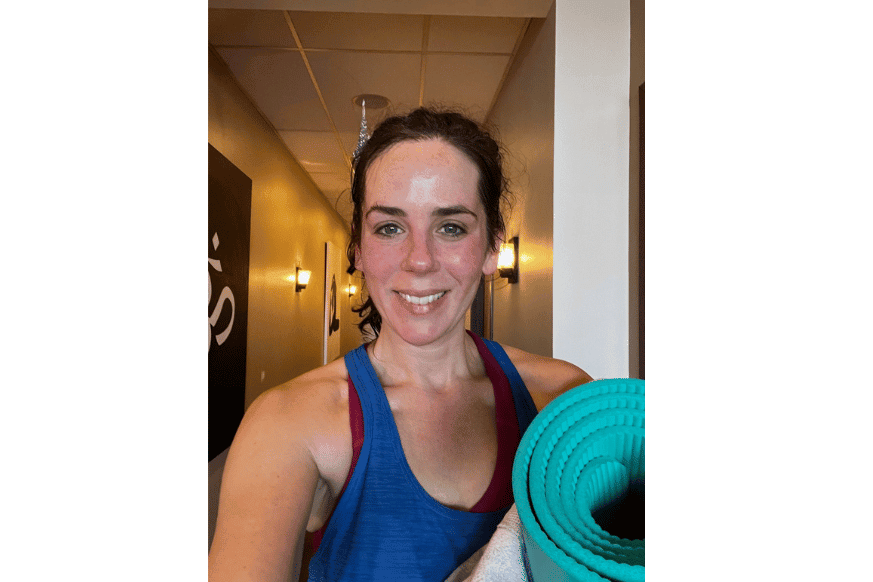 Natalie Kalmar smiling while holding her yoga mat after taking a class at Sumits Hot Yoga.  Glowing from sweating for 60 mins.