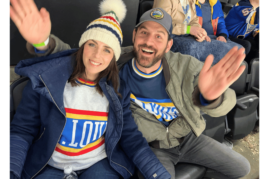 natalie and mitchell kalmar having fun at the blues game, dressed warmly in blues sweatshirts and hats.  