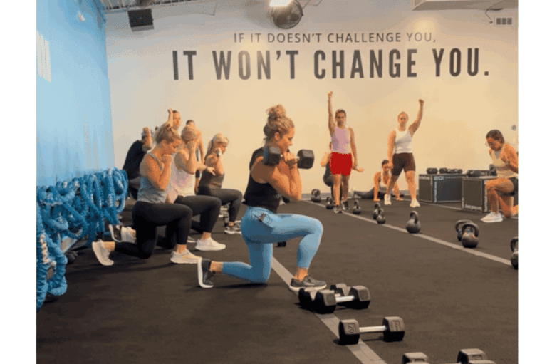 A group of women doing squats with dumbbells.