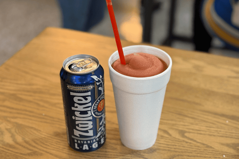 2 drinks shown available at Enterprise Center for purchase, on the left a blue beer can and on the right a white stroafoam cup with a pink frozen drink and red straw