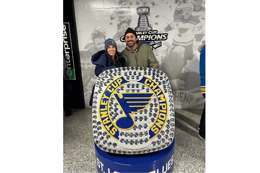 husband and wife posing with enlarged STL championship ring