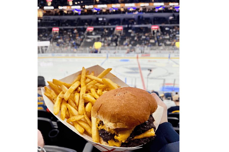 Enterprise Center St Louis Blues game game as backdrop with Hi-Pointe double cheese burger and french fries in foreground.