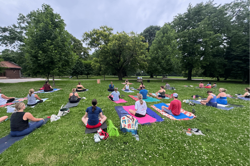 several yoga participants seated on colorful yoga mats in the park