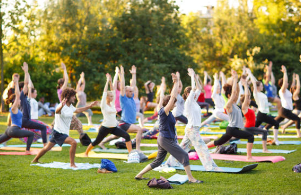 A diverse group of people of various ages practicing yoga in the park