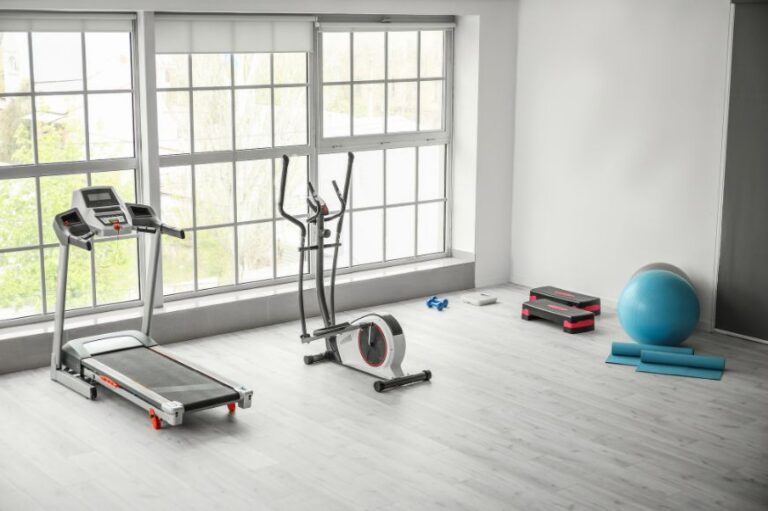 home gym set up near a window with a treadmill, and eliptical machine