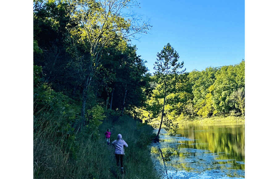 mom and child shown hiking alongside Lake Lincoln. Lush greenery dots the gravel trail