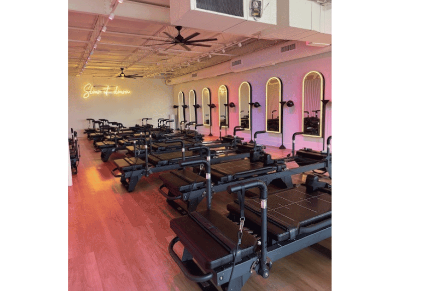 peek inside a brand new reformer pilates studio with modern lighting, mirrors and megareformers in des peres a suburb of st. louis. 12 empty reformers shown