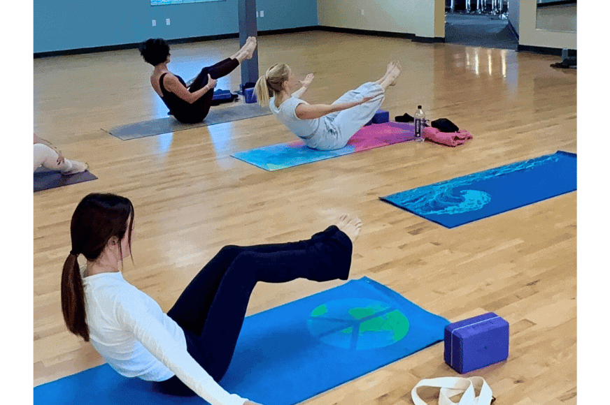 3 women holding boat bose during a yoga class