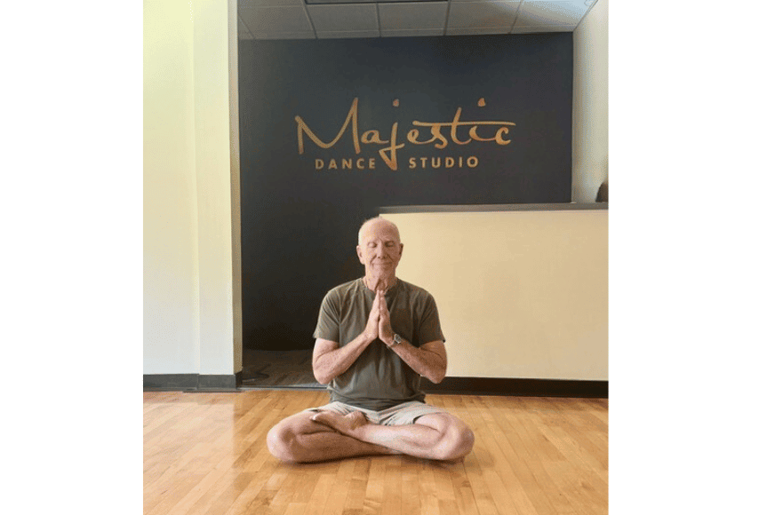 Emmet Schmelig, has been a passionate yogi for over 30 years and is shown teaching core strength and yoga poses to students of all ages in a clean dance studio