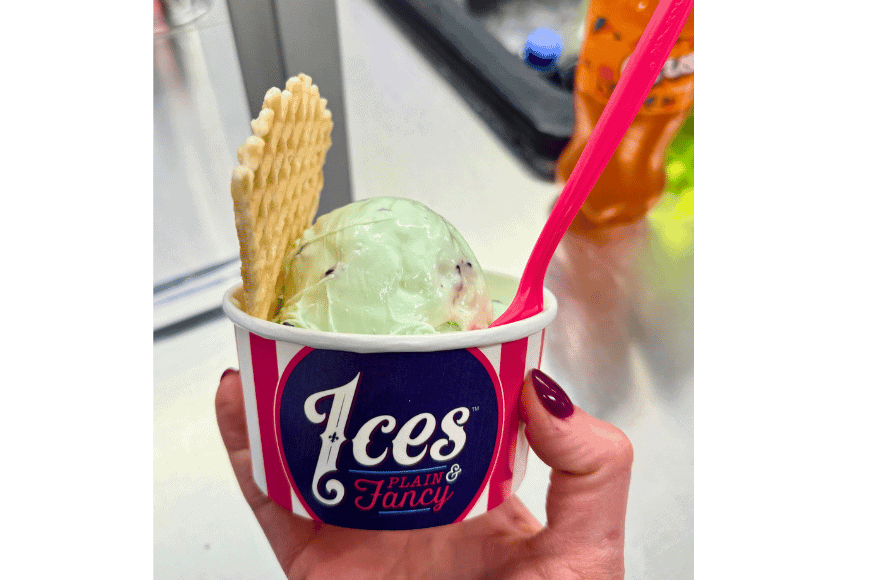 a cup of greenish white ice cream with a waffle cone cookie and pink spoon