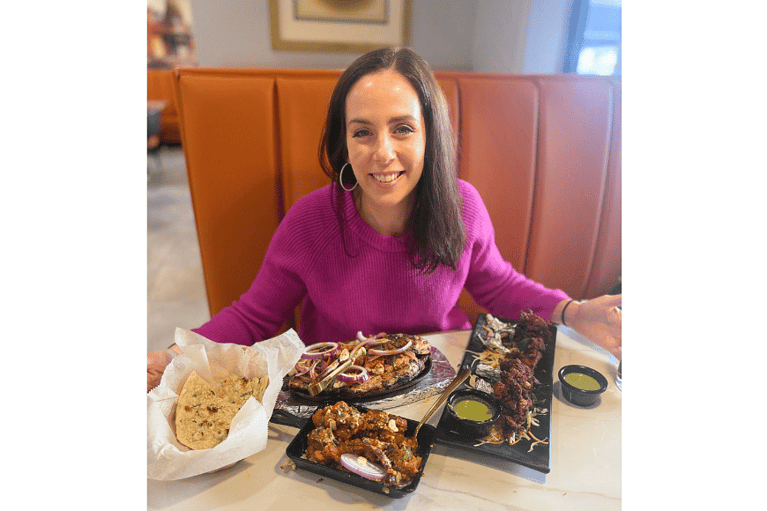 natalie kalmar, aka fitnessfoodiestl, smiles in front of her feast at persis indian grill now open in ballwin, mo.