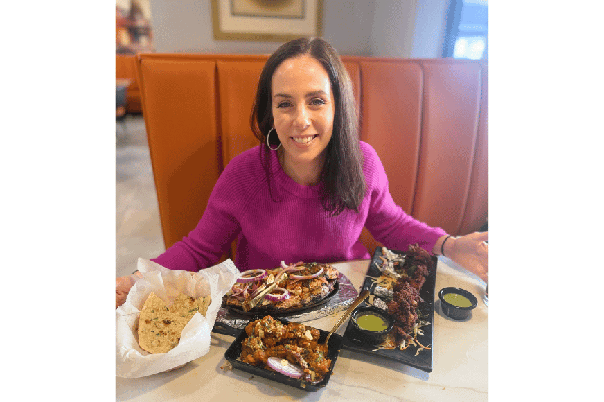 natalie kalmar, aka fitnessfoodiestl, smiles in front of her feast at persis indian grill now open in ballwin, mo.