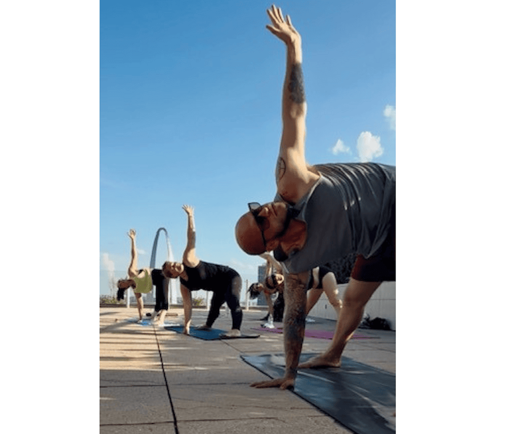 rooftop at four seasons hotel where a group gathers for outdoor yoga with the arch as a backdrop