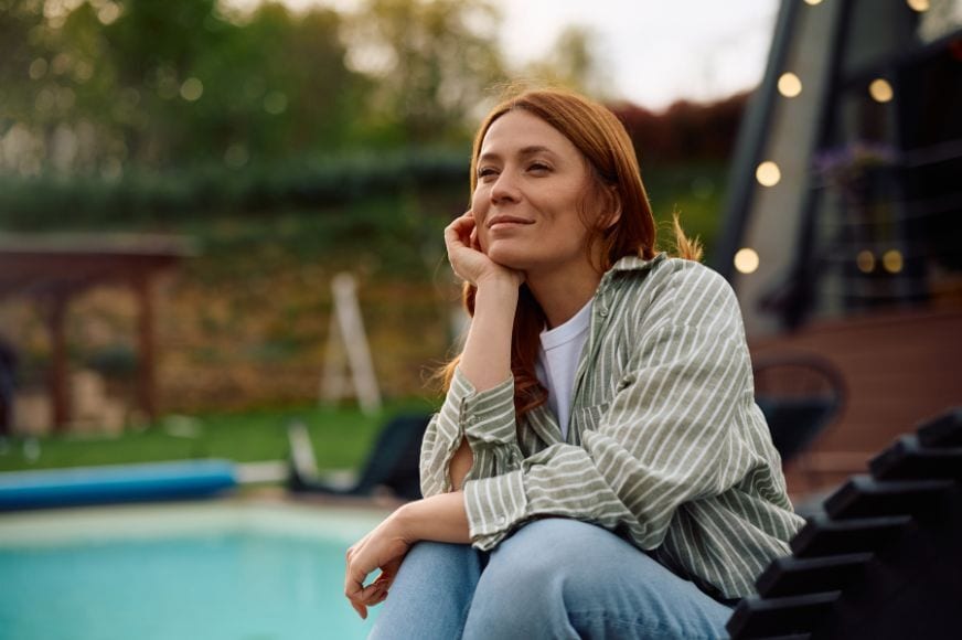 women sitting outside relaxing her her backyard space